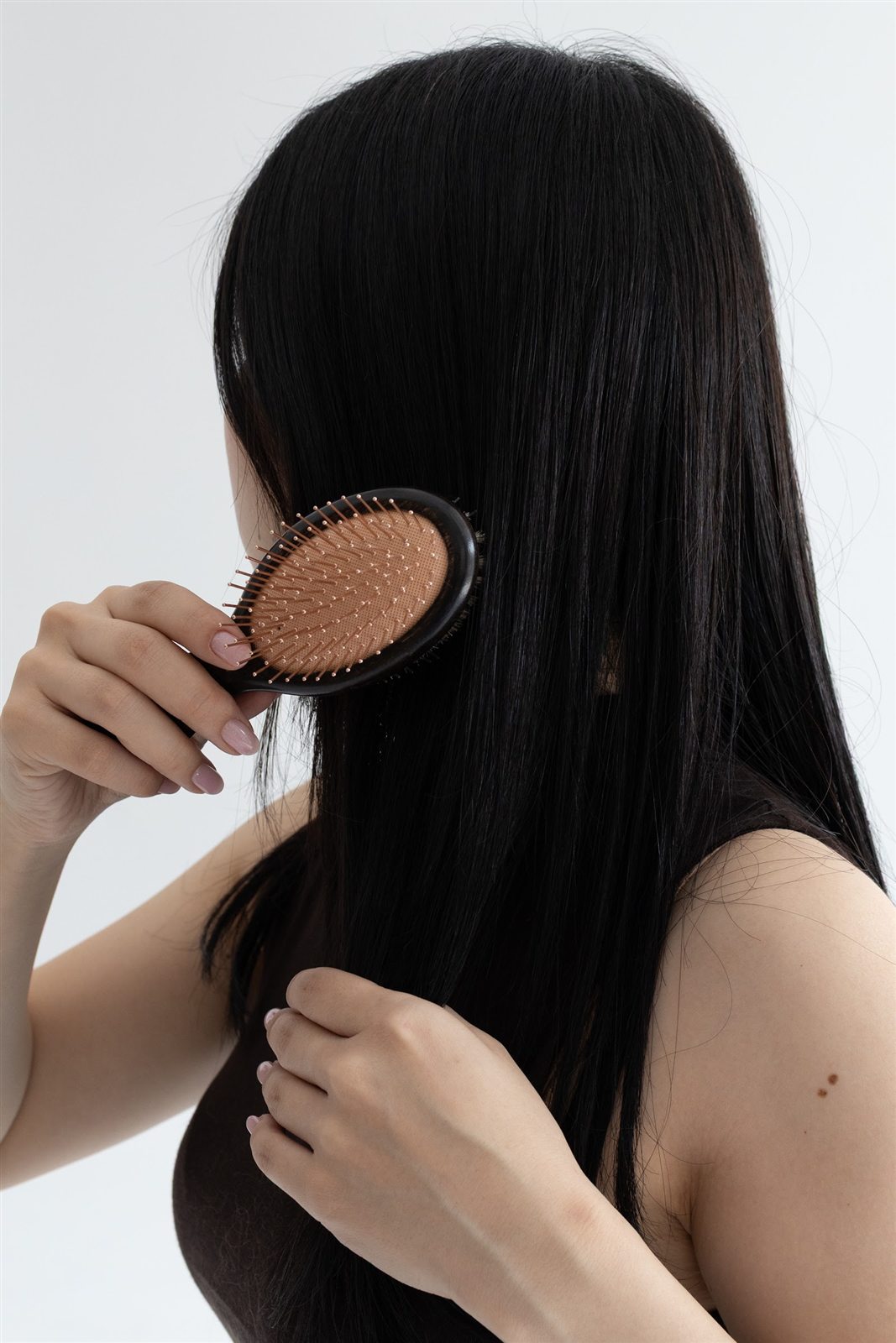 ヘアブラシで長い黒髪を梳かす後ろ姿
